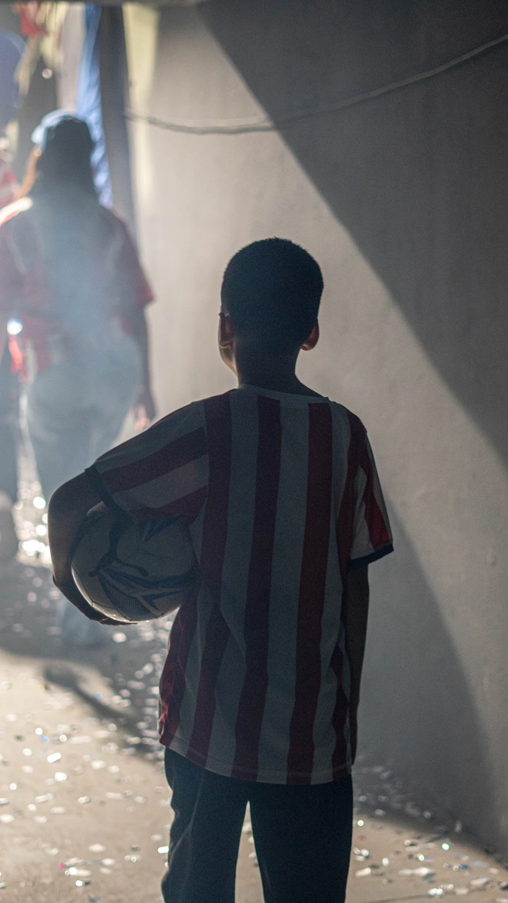 Niño con la pelota en el túnel iluminado, entre el humo y un haz de luz