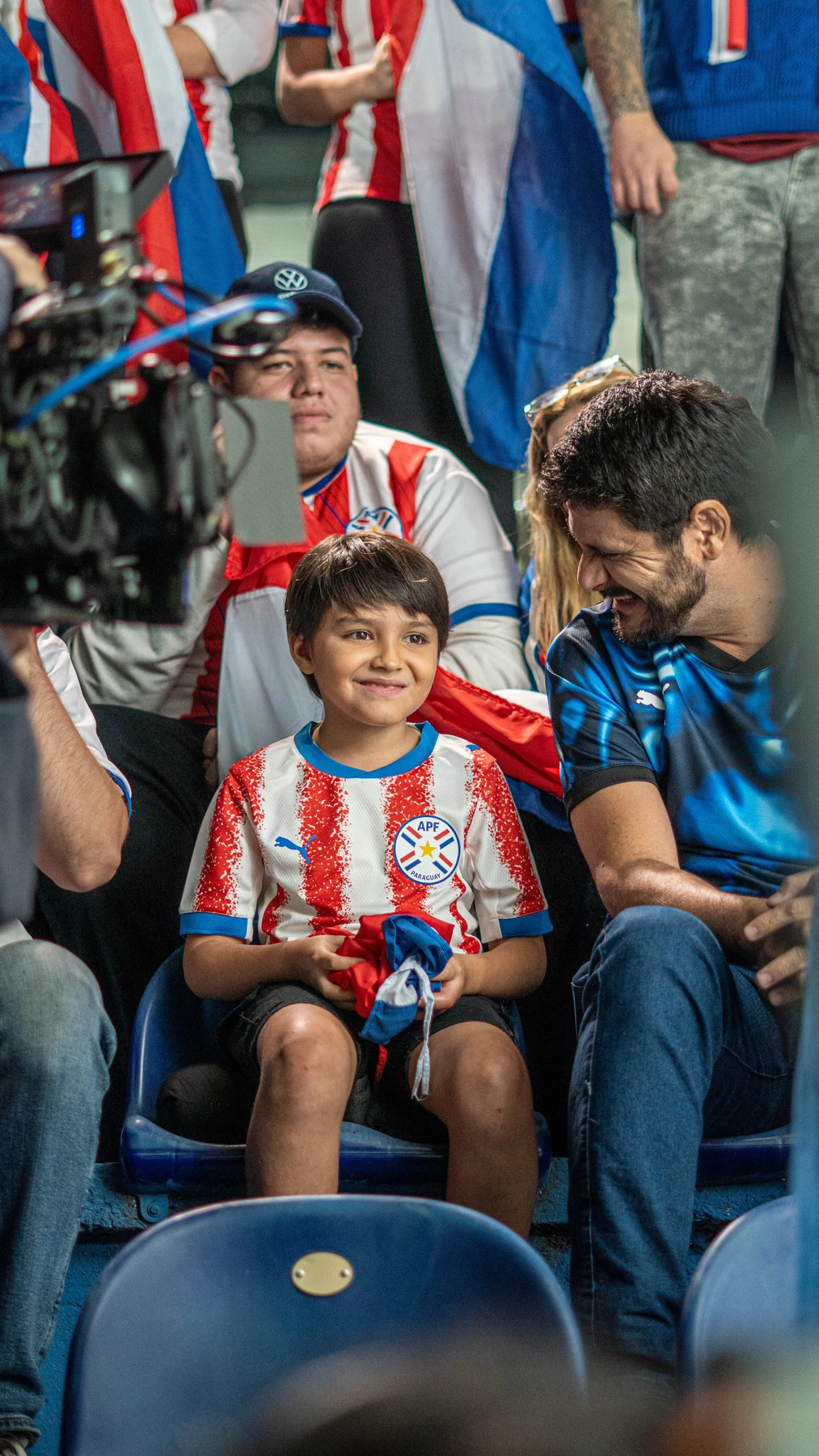 Niño con camiseta de Paraguay sentado junto a cámara y equipo durante el rodaje
